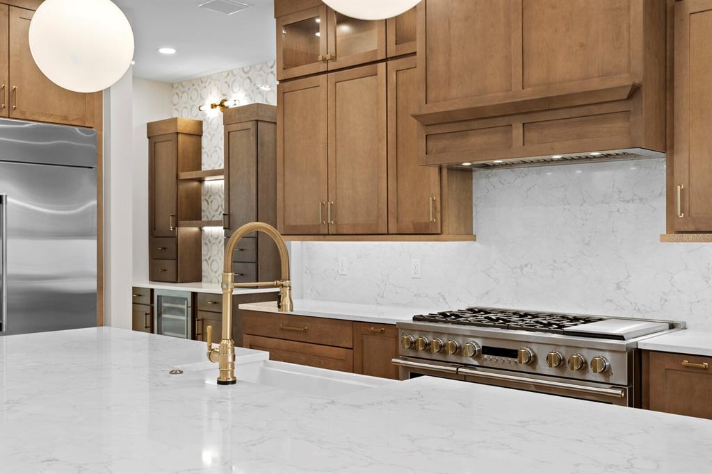 A modern kitchen features wood cabinets, white marble countertops, a gas range, and gold fixtures — 5021 W LEONA STREET, TAMPA, FL