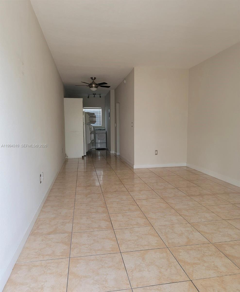 An open-concept living area features beige tile flooring and a view toward a kitchen — 620 76th St # 11, Miami Beach FL 33141, MIAMI BEACH, FL