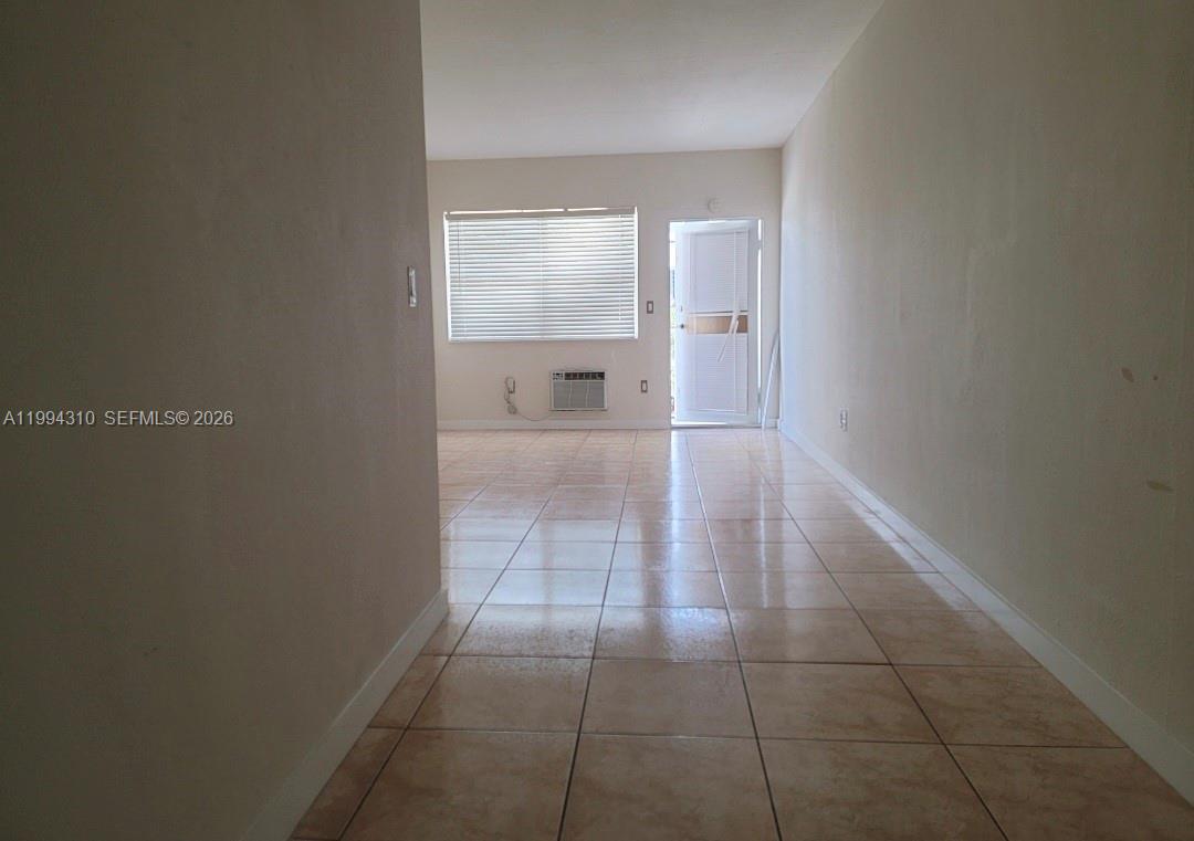 A tiled hallway leads into a living area with a window, air conditioner, and door — 620 76th St # 11, Miami Beach FL 33141, MIAMI BEACH, FL