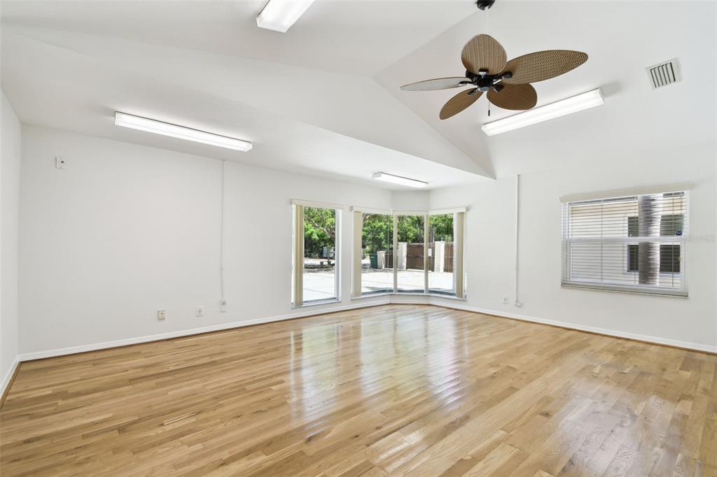 A bright, empty room with hardwood floors, a vaulted ceiling, and a ceiling fan — 670 2ND STREET N, SAFETY HARBOR, FL