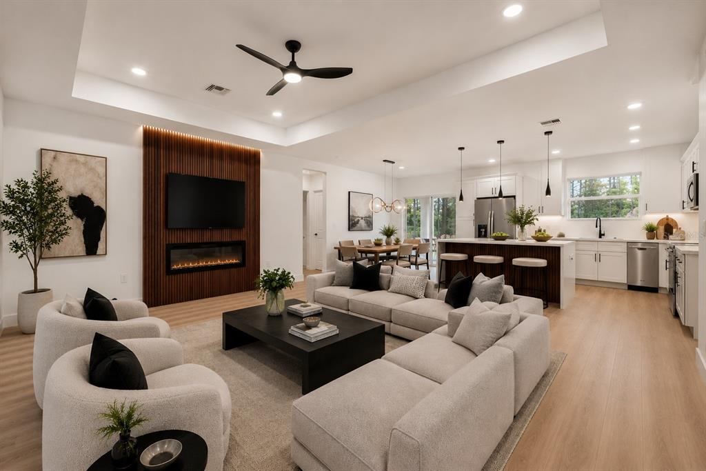 An open-concept living room features a slatted wood fireplace wall, light flooring, and a kitchen — 4225 GERONA AVENUE, SEBRING, FL