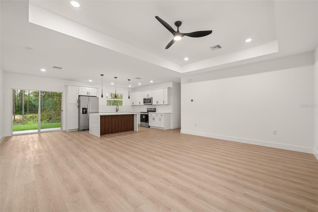 An open-concept kitchen and living area features white cabinetry, a wood-slatted island, and light flooring — 4225 GERONA AVENUE, SEBRING, FL