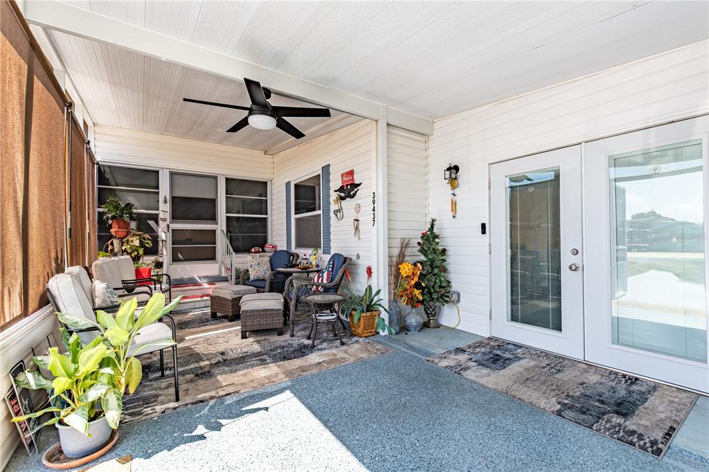 A covered patio features a ceiling fan, outdoor furniture, potted plants, and white siding — 39437 ELGIN DRIVE, ZEPHYRHILLS, FL