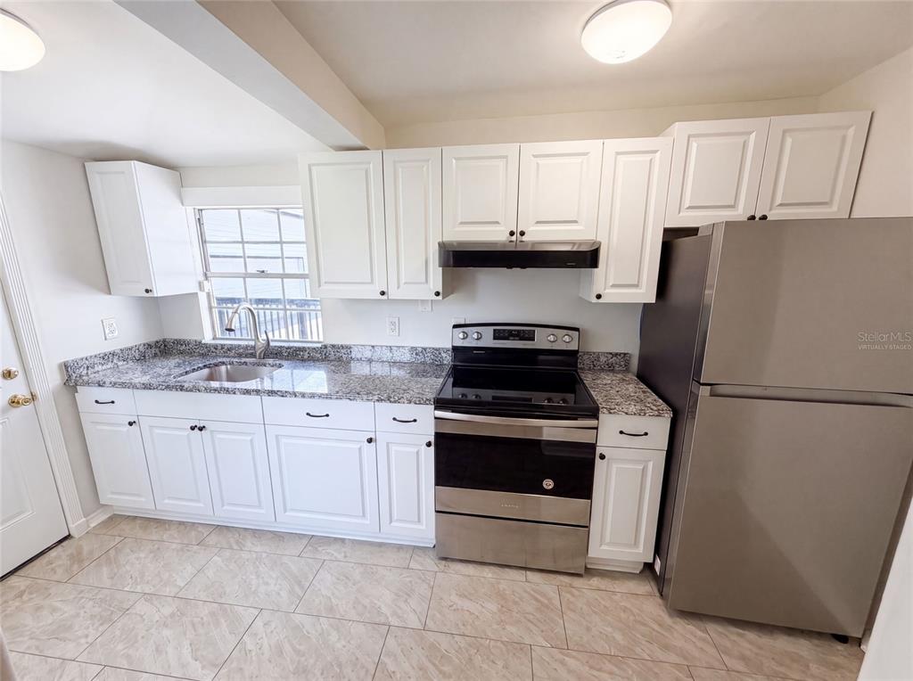 A kitchen features white cabinets, granite countertops, stainless steel appliances, and light-colored tile flooring — 111 S OLEANDER AVENUE, SANFORD, FL