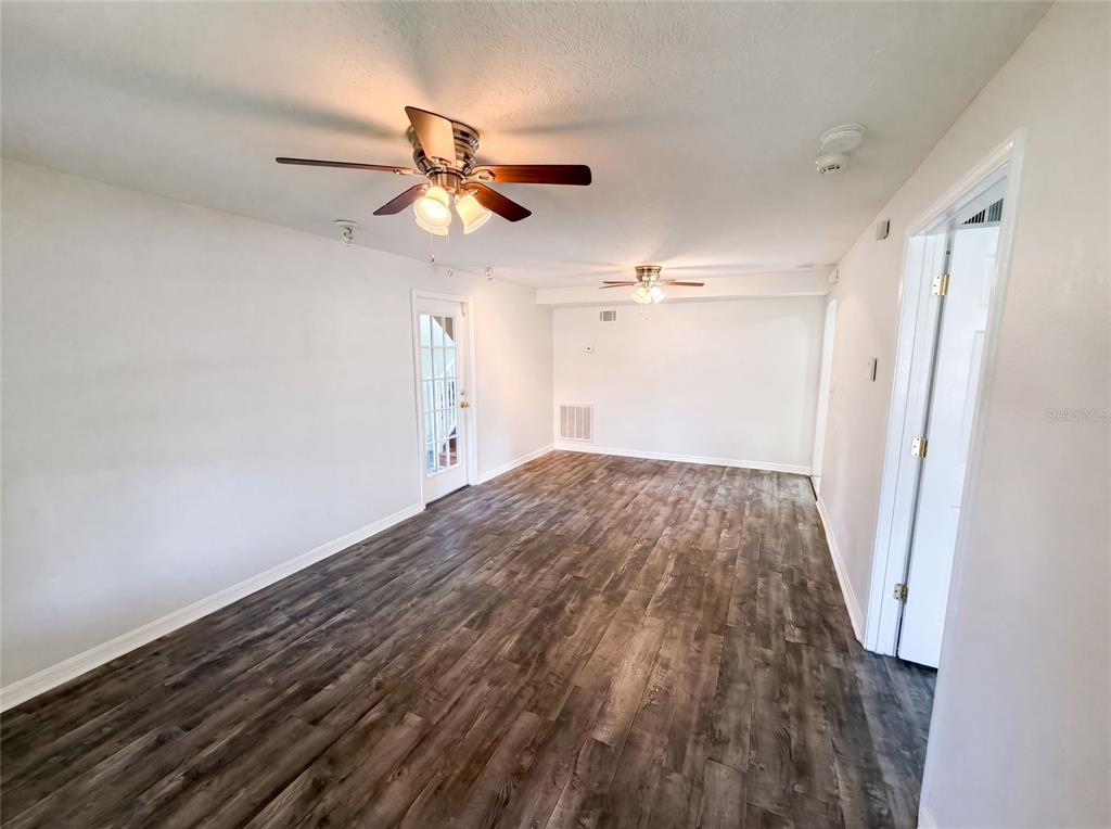 An empty room with wood-look flooring, two ceiling fans, and a glass-paned door — 111 S OLEANDER AVENUE, SANFORD, FL