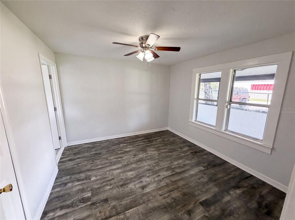 An empty bedroom features light gray walls, dark wood-look flooring, and a ceiling fan — 111 S OLEANDER AVENUE, SANFORD, FL