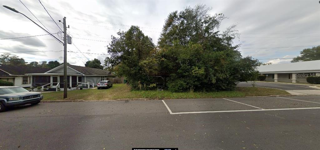 A vacant, tree-covered lot sits between a residential house and a commercial building — 5279 BROWN STREET, GRACEVILLE, FL