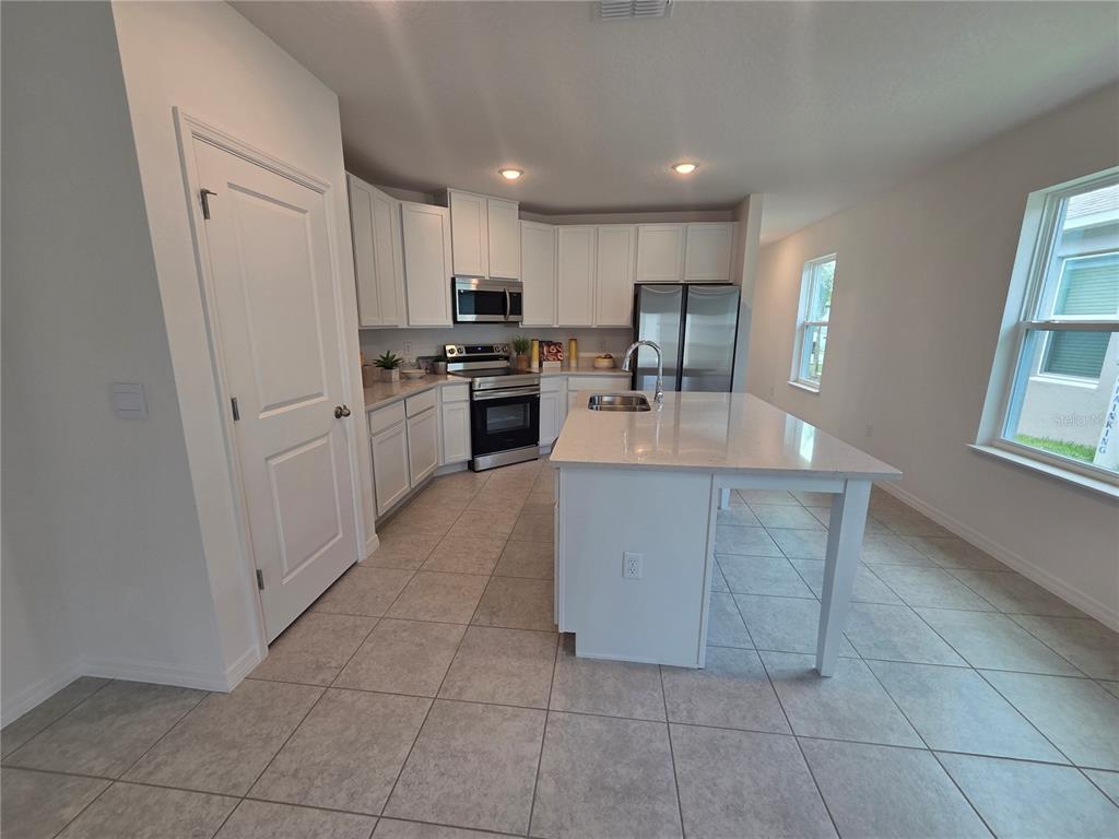 A modern kitchen features white cabinets, stainless steel appliances, and a large central island — 2747 SAN MARCO WAY, WINTER HAVEN, FL