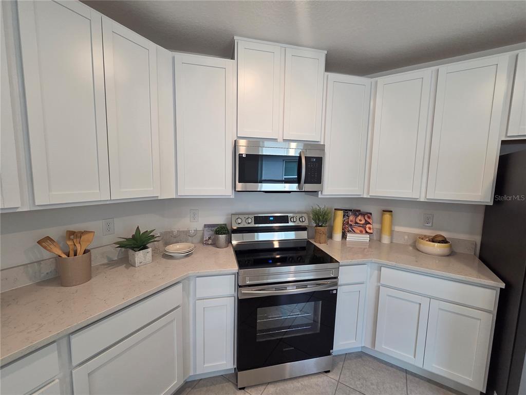 A kitchen features white cabinets, stainless steel appliances, and light-colored countertops — 2747 SAN MARCO WAY, WINTER HAVEN, FL