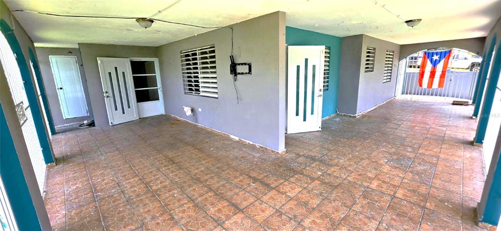 A covered patio with tiled flooring, gray walls, and multiple white doors — 8 CALLE CASCADA, SAN LORENZO, PR