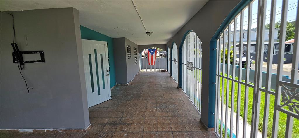 A covered patio features tiled flooring, arched security gates, and a white door — 8 CALLE CASCADA, SAN LORENZO, PR