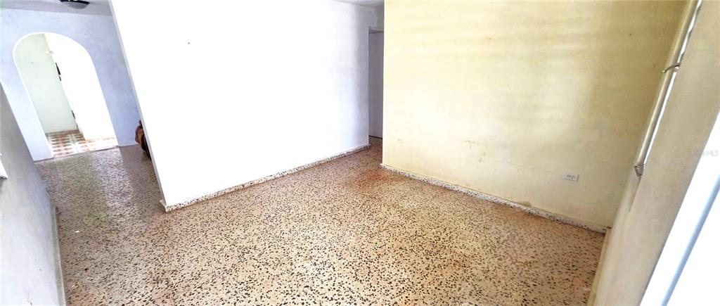 An empty room features white walls, a yellow accent wall, and speckled terrazzo flooring — 8 CALLE CASCADA, SAN LORENZO, PR