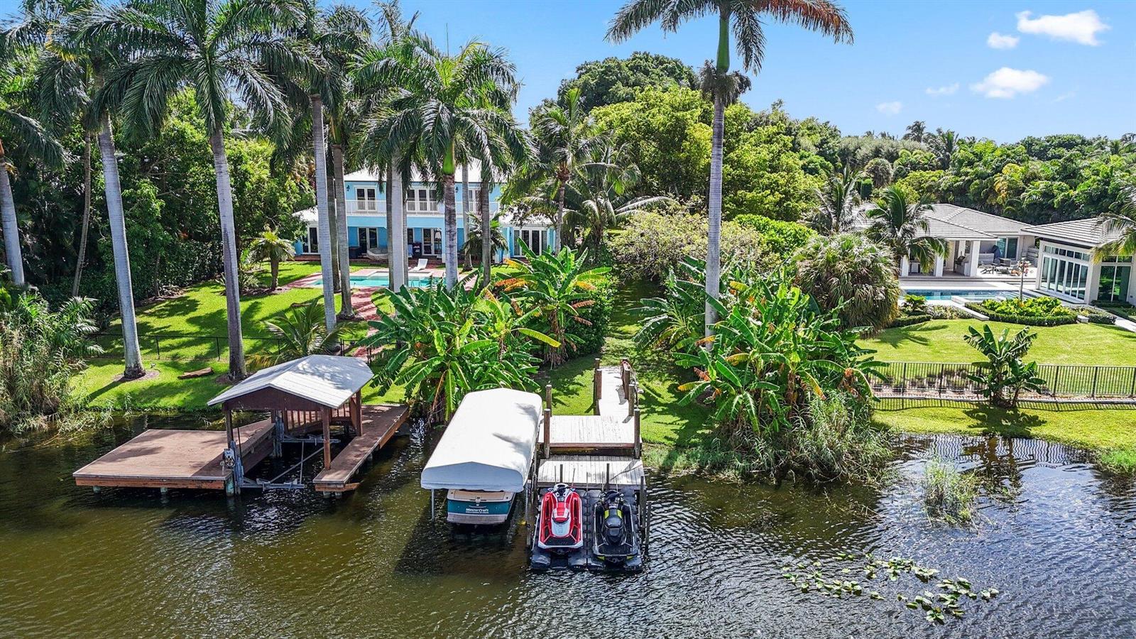 An aerial view shows two waterfront houses with docks, boat lifts, and lush tropical landscaping — 920 Hibiscus Lane, Delray Beach FL 33444, DELRAY BEACH, FL
