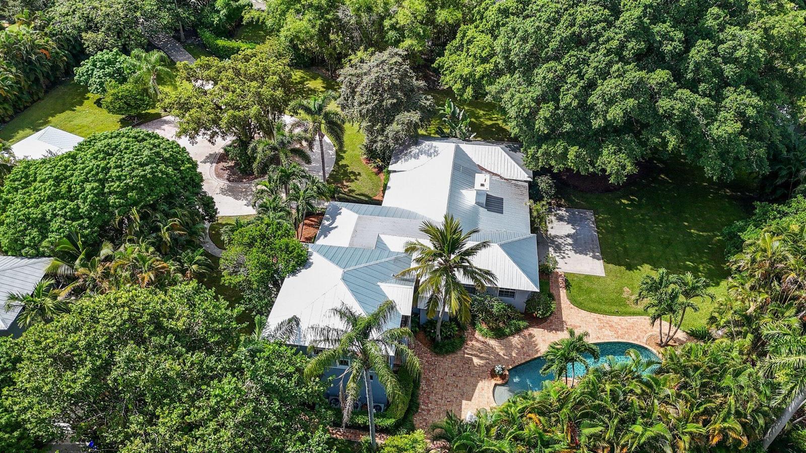 An aerial view shows a house with a metal roof, swimming pool, and lush landscaping — 920 Hibiscus Lane, Delray Beach FL 33444, DELRAY BEACH, FL