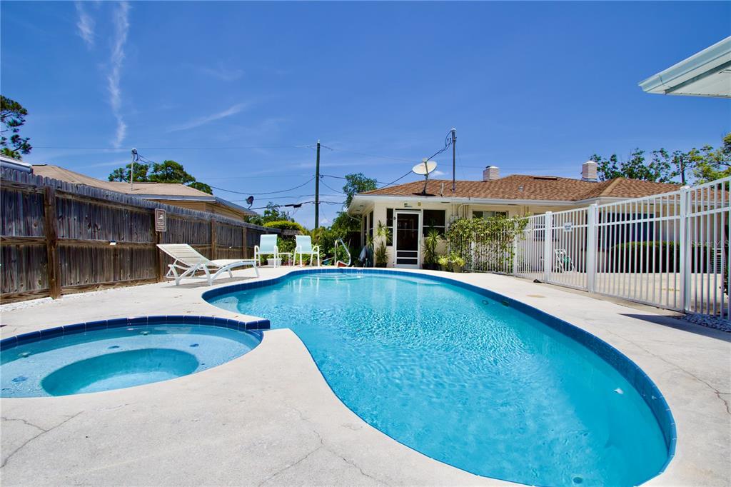 A backyard swimming pool and attached spa are surrounded by a concrete deck and fence — 411 PLEASANT STREET, CLEARWATER, FL