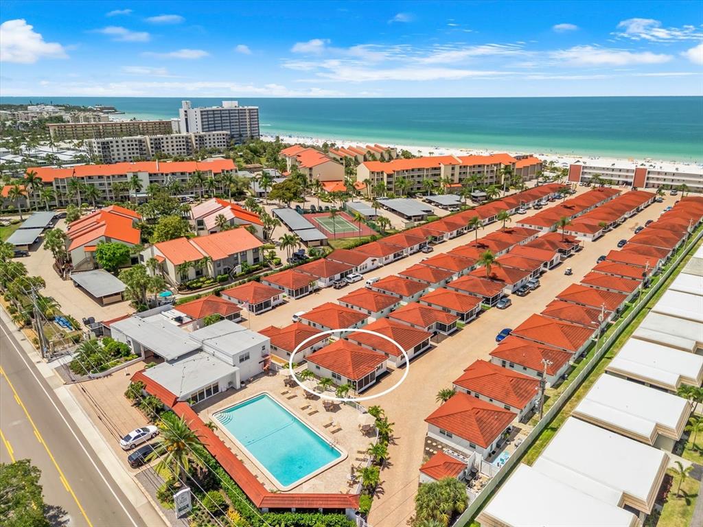 An aerial view shows a residential complex with red-tiled roofs near a beach — 6154 MIDNIGHT PASS ROAD UNIT B1, SARASOTA, FL