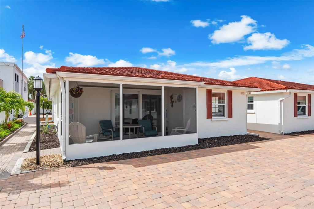 A white house with a red tile roof features a screened-in porch and paver driveway — 6154 MIDNIGHT PASS ROAD UNIT B1, SARASOTA, FL
