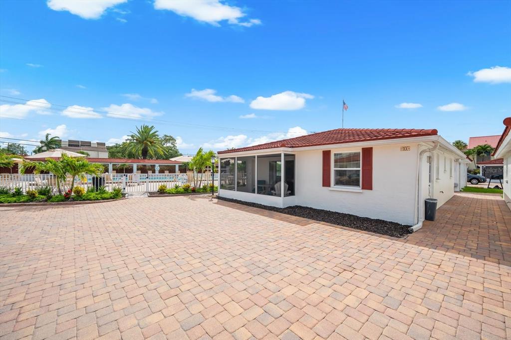A white house with a red tile roof and a screened-in porch faces a brick-paved courtyard — 6154 MIDNIGHT PASS ROAD UNIT B1, SARASOTA, FL