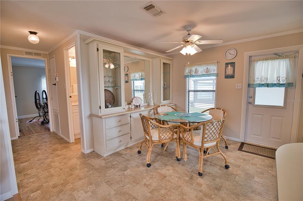 A dining area features a glass-topped table with wicker chairs, a hutch, and tile flooring — 632 LA JOLLA CIRCLE, NORTH PORT, FL