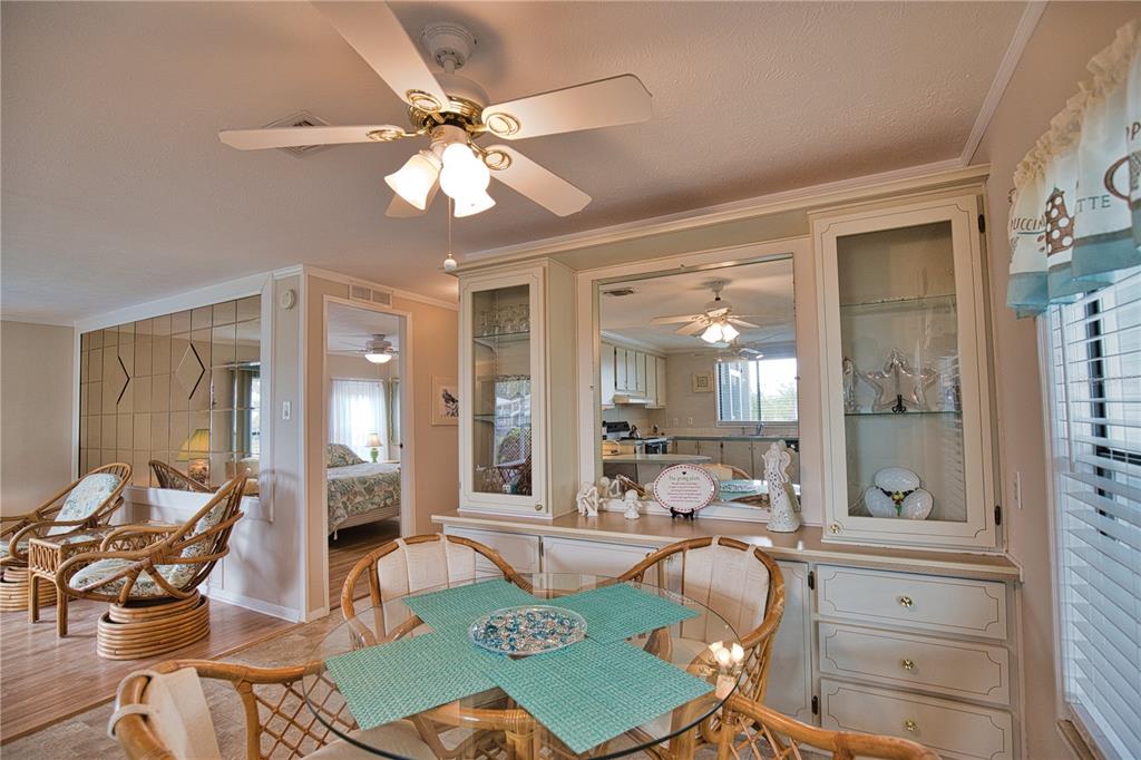 A dining area features a glass table, rattan chairs, and built-in cabinetry with mirrored accents — 632 LA JOLLA CIRCLE, NORTH PORT, FL