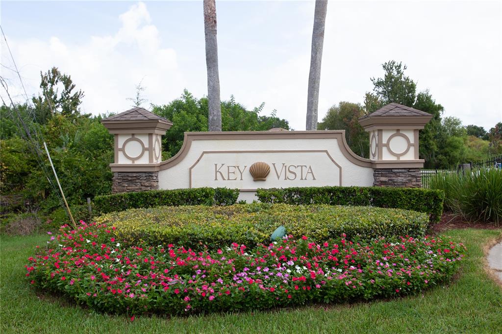 A stone and stucco monument sign for Key Vista sits behind a bed of flowers — 2815 WOOD POINTE DRIVE, HOLIDAY, FL