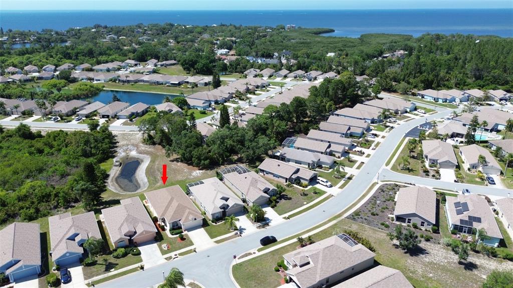 An aerial view shows a suburban neighborhood with single-family homes near a body of water — 2815 WOOD POINTE DRIVE, HOLIDAY, FL