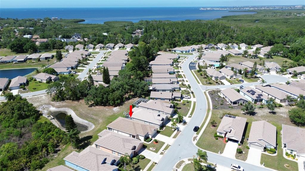 An aerial view shows a residential neighborhood with single-family homes near a coastal body — 2815 WOOD POINTE DRIVE, HOLIDAY, FL