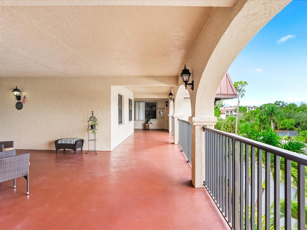 A covered balcony with a red floor, metal railings, and arched architectural details — 23465 HARBORVIEW ROAD UNIT 235, PUNTA GORDA, FL