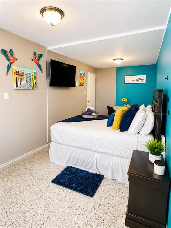 A bedroom features a bed with blue and yellow pillows, a welcome sign, and turquoise walls — CII Via 18 Apt 2 VILLA FONTANA, CAROLINA, PR