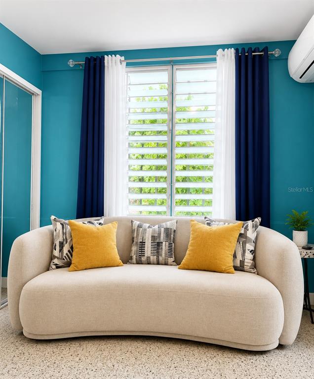 A curved beige sofa sits in front of a window with blue and white curtains — CII Via 18 Apt 2 VILLA FONTANA, CAROLINA, PR