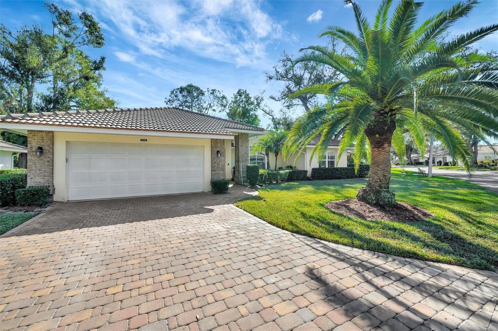 A single-story house with a tiled roof, a brick paver driveway, and a large palm tree — 5721 GARDEN LAKES MAJESTIC, BRADENTON, FL
