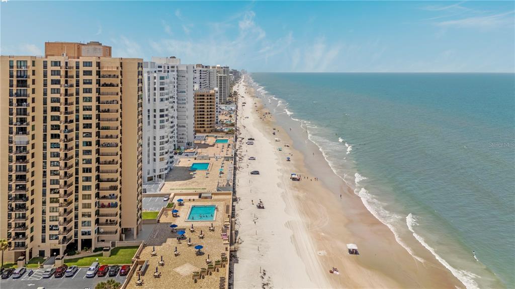 An aerial view of a sandy beach lined with high-rise apartment buildings and swimming pools — 3051 S ATLANTIC AVENUE UNIT 1705, DAYTONA BEACH SHORES, FL