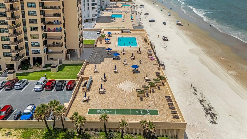 An aerial view shows a high-rise building with a pool deck, shuffleboard court, and beach — 3051 S ATLANTIC AVENUE UNIT 1705, DAYTONA BEACH SHORES, FL