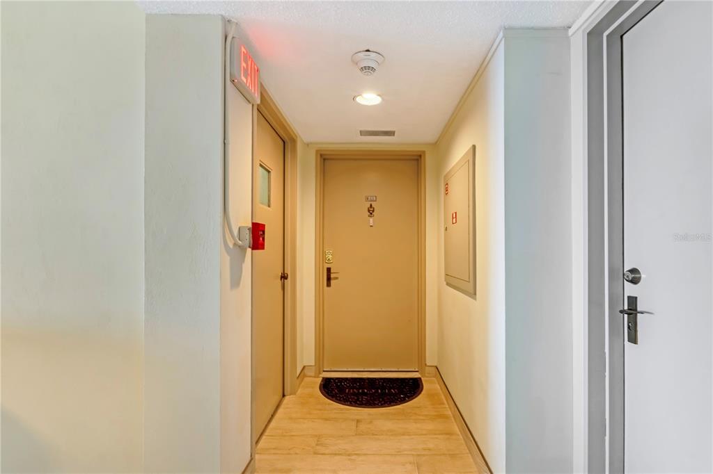 A hallway features light wood-look flooring, a central tan door, and a white ceiling — 3051 S ATLANTIC AVENUE UNIT 1705, DAYTONA BEACH SHORES, FL