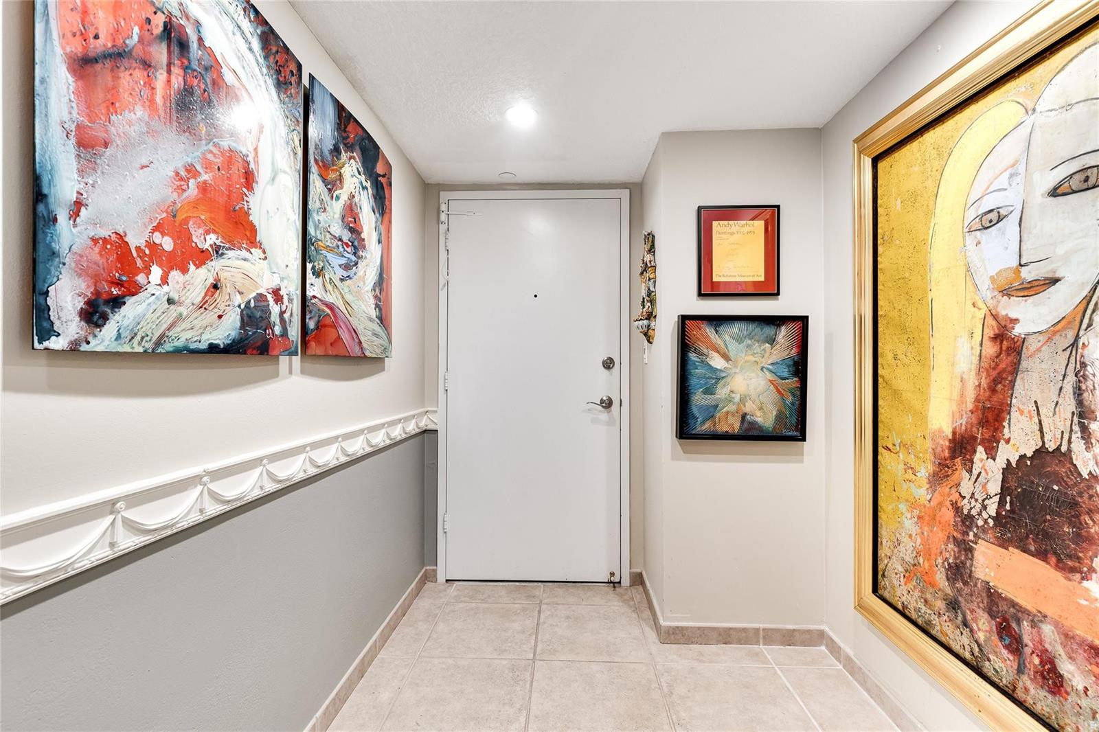 A hallway features tile flooring, a white door, and several framed artworks on the walls — 2500 E Las Olas Boulevard # 609, Fort Lauderdale FL 33301, FORT LAUDERDALE, FL