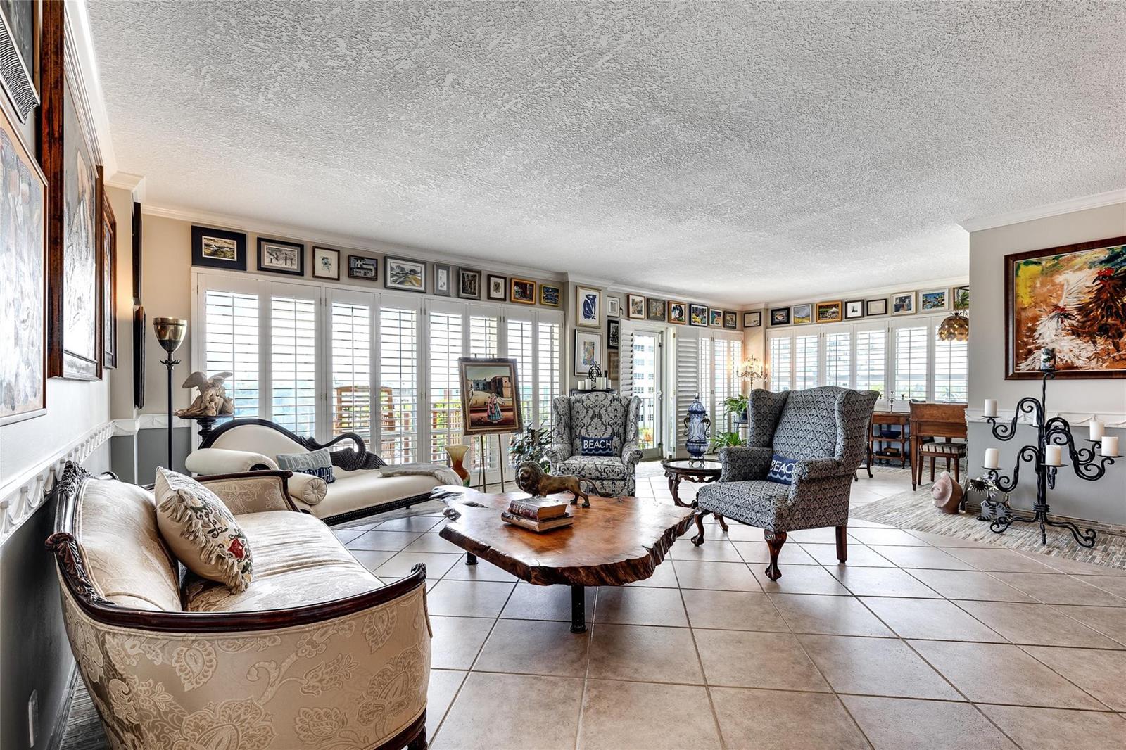 A living room features tile floors, a live-edge coffee table, and walls lined with framed art — 2500 E Las Olas Boulevard # 609, Fort Lauderdale FL 33301, FORT LAUDERDALE, FL
