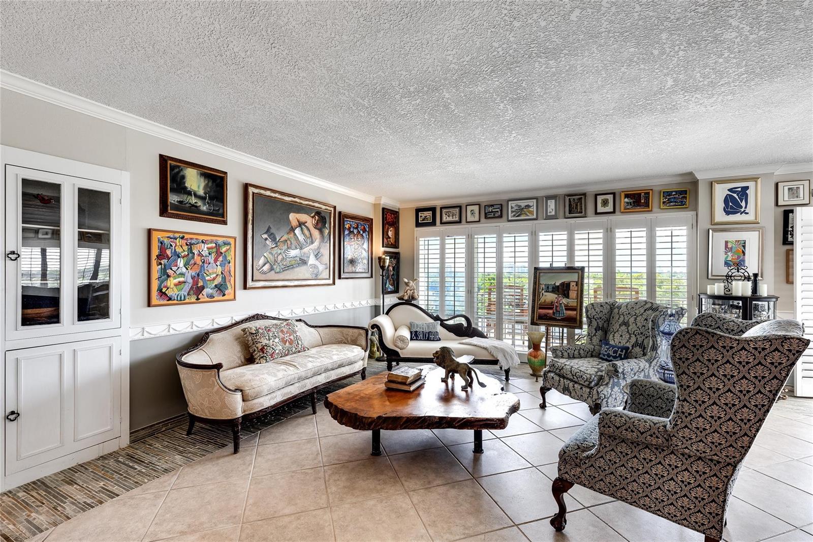 A living room features tiled floors, a live-edge coffee table, and numerous framed wall artworks — 2500 E Las Olas Boulevard # 609, Fort Lauderdale FL 33301, FORT LAUDERDALE, FL