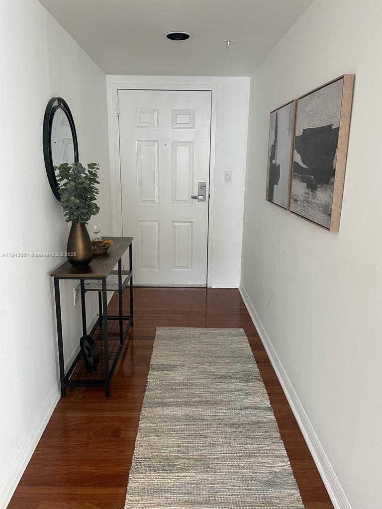 A narrow entryway features hardwood floors, a console table, a mirror, and two wall art pieces — 1155 Brickell Bay Dr # 2802, Miami FL 33131, MIAMI, FL