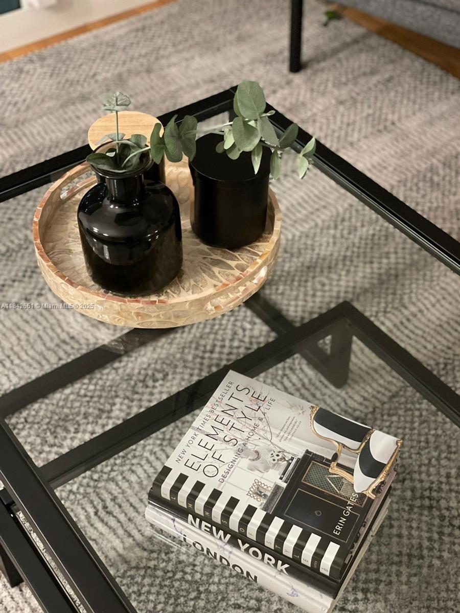 A glass-topped coffee table holds a decorative tray with vases and a stack of books — 1155 Brickell Bay Dr # 2802, Miami FL 33131, MIAMI, FL