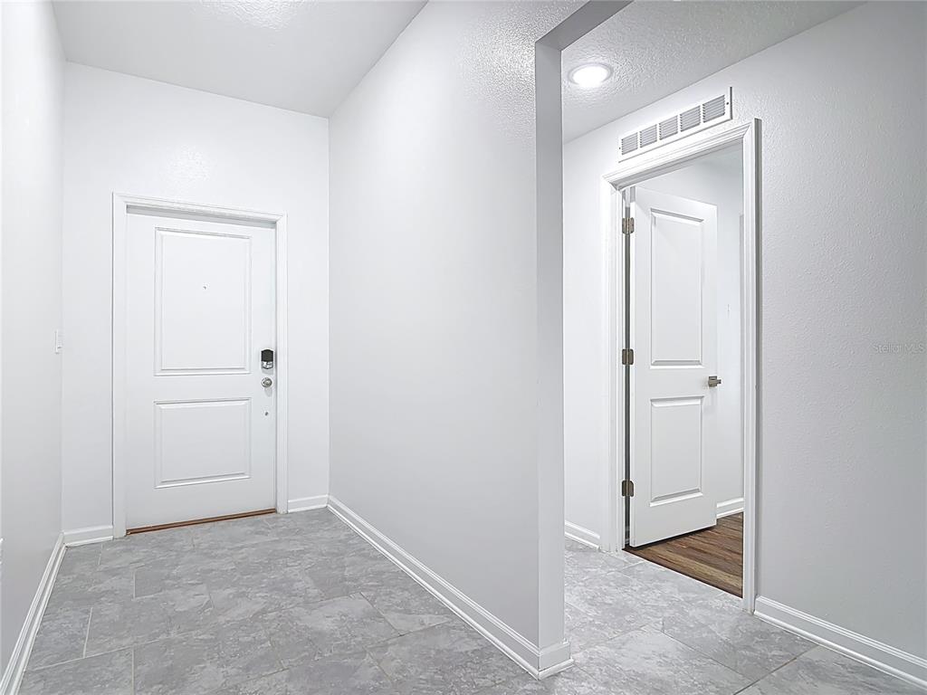 An entryway features gray tile flooring, white walls, and a white door — 1312 PEACH CREEK DRIVE, OSTEEN, FL