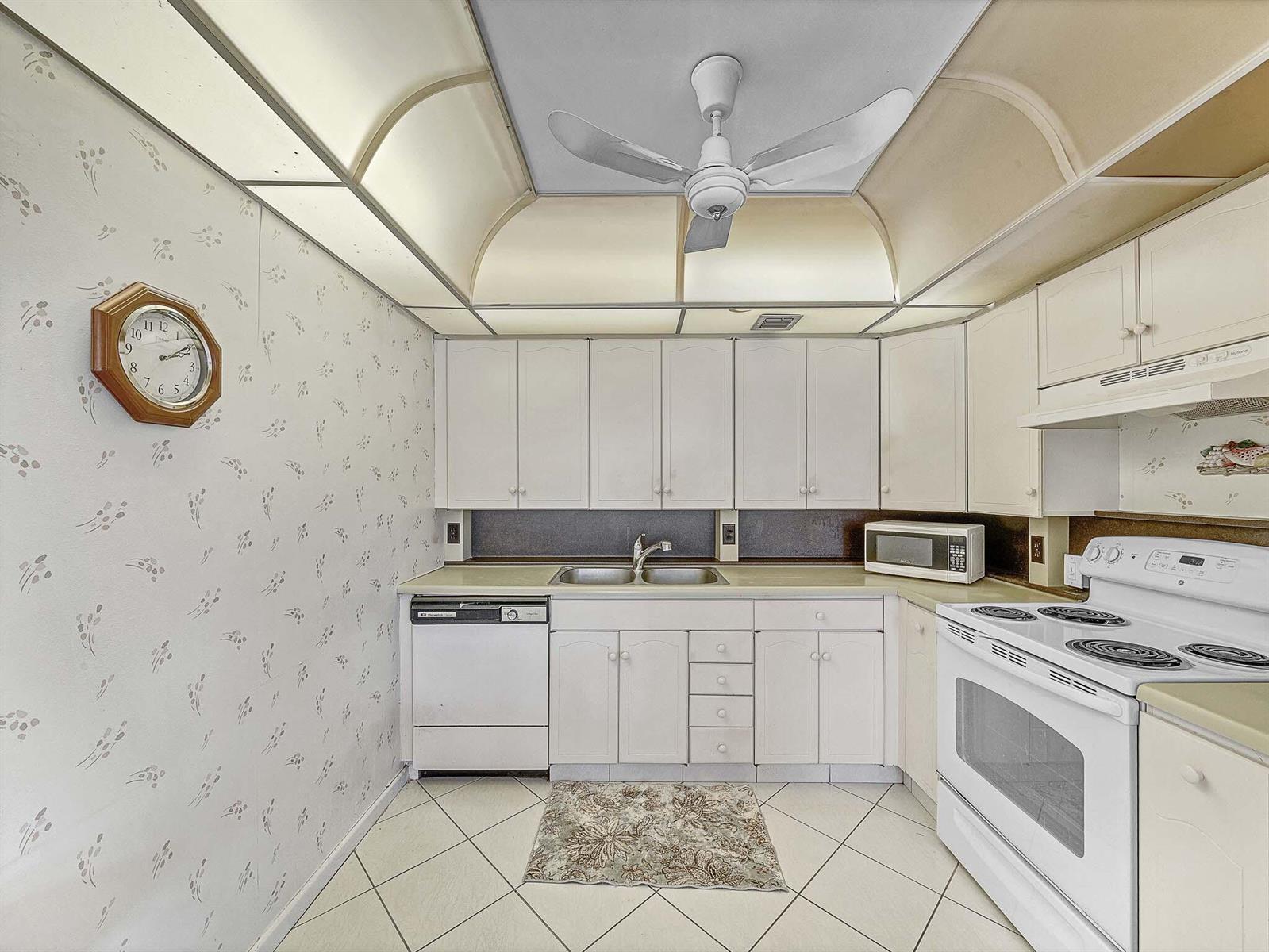 A kitchen with white cabinets, a ceiling fan, patterned wallpaper, and a white stove — 3002 Ventnor # G, Deerfield Beach FL 33442, DEERFIELD BEACH, FL