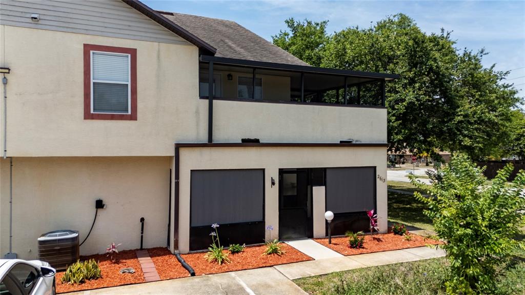 The exterior of a two-story residential building features a covered balcony and a screened-in patio — 2613 S PARK AVENUE, TITUSVILLE, FL