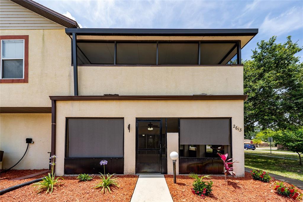 The exterior of a two-story townhouse features a screened-in porch and a second-floor balcony — 2613 S PARK AVENUE, TITUSVILLE, FL