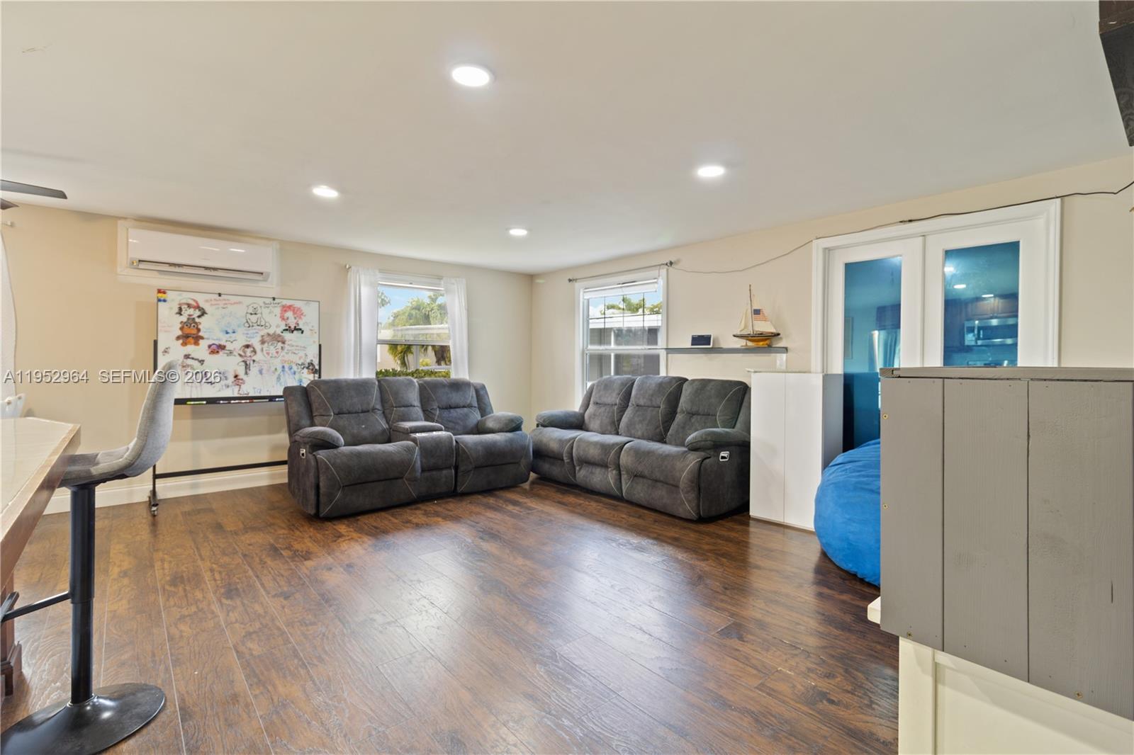 A living room features dark wood flooring, two gray reclining sofas, and a whiteboard — 5720 SW Cypress Dr, Dania Beach FL 33312, DANIA BEACH, FL