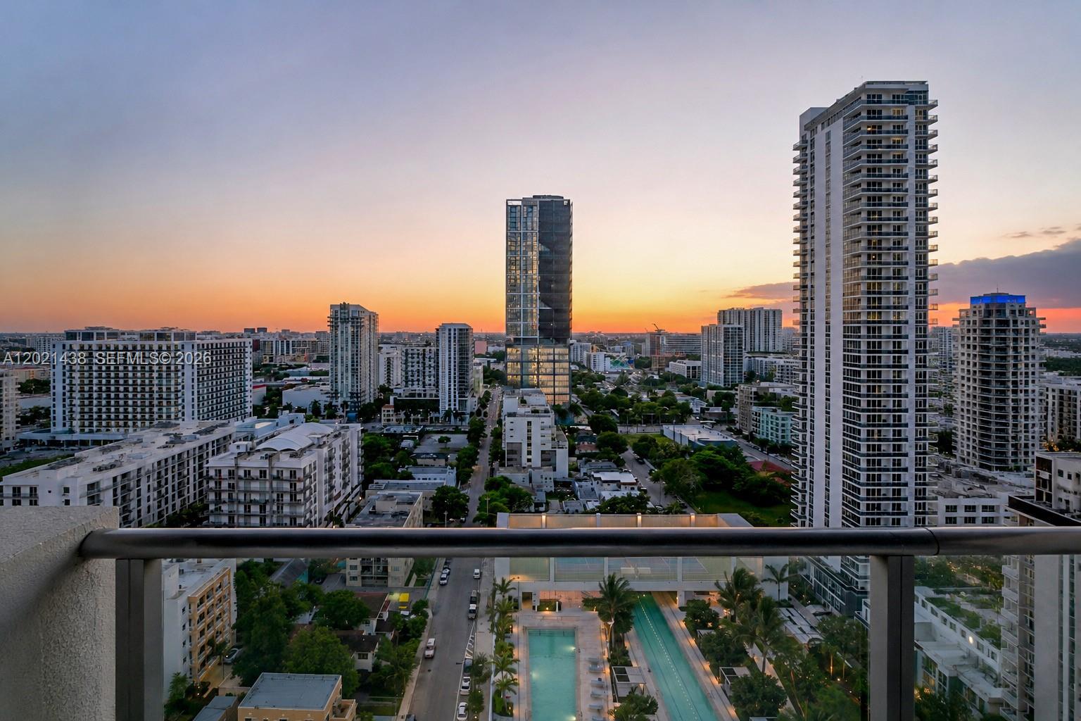 A modern living room features a grey sectional sofa, a wall-mounted television, and floor-to-ceiling windows — 700 NE 26th Ter # 2105, Miami FL 33137, MIAMI, FL