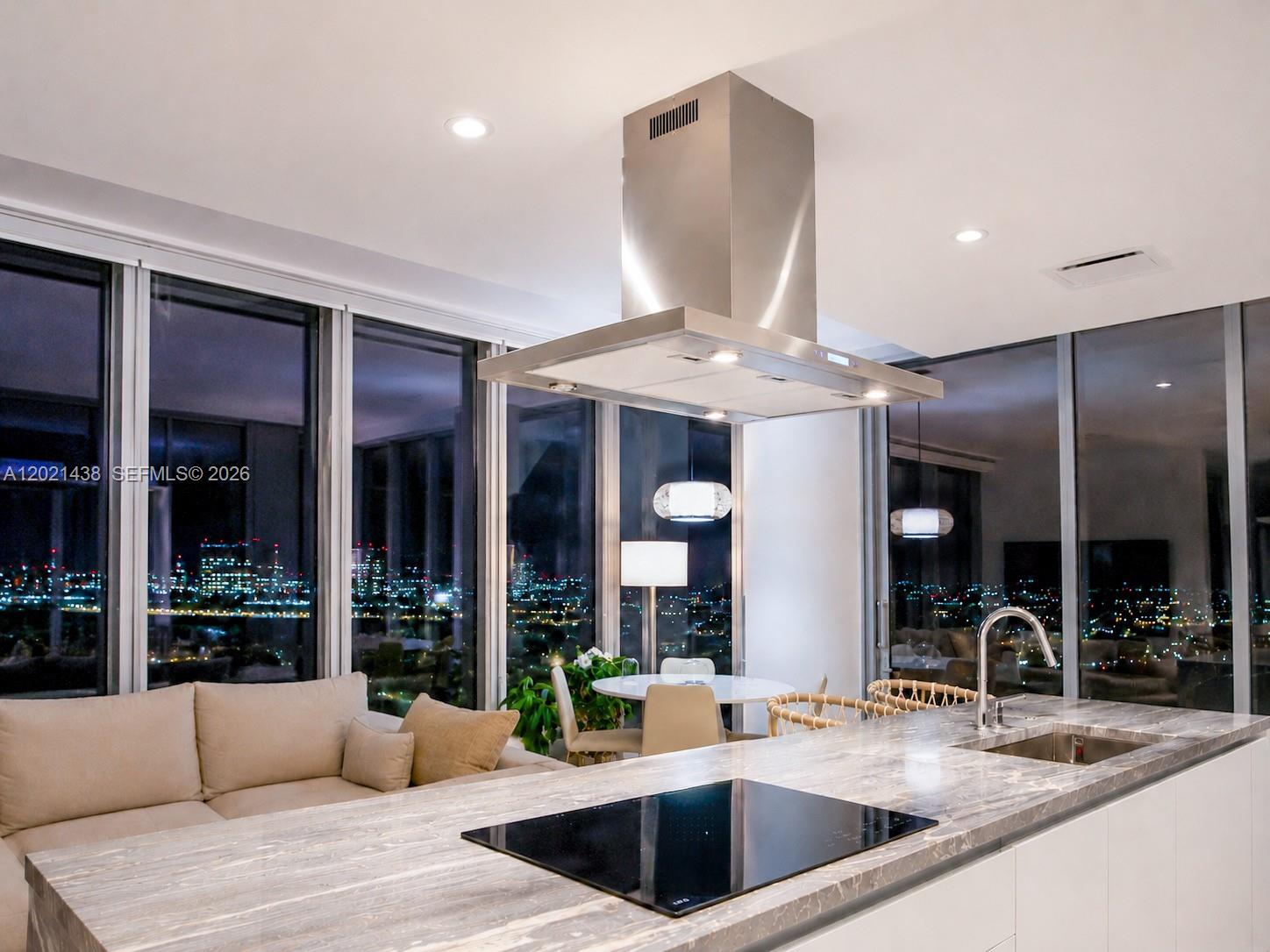 A modern bedroom features a gray upholstered bed, a red armchair, and floor-to-ceiling windows — 700 NE 26th Ter # 2105, Miami FL 33137, MIAMI, FL