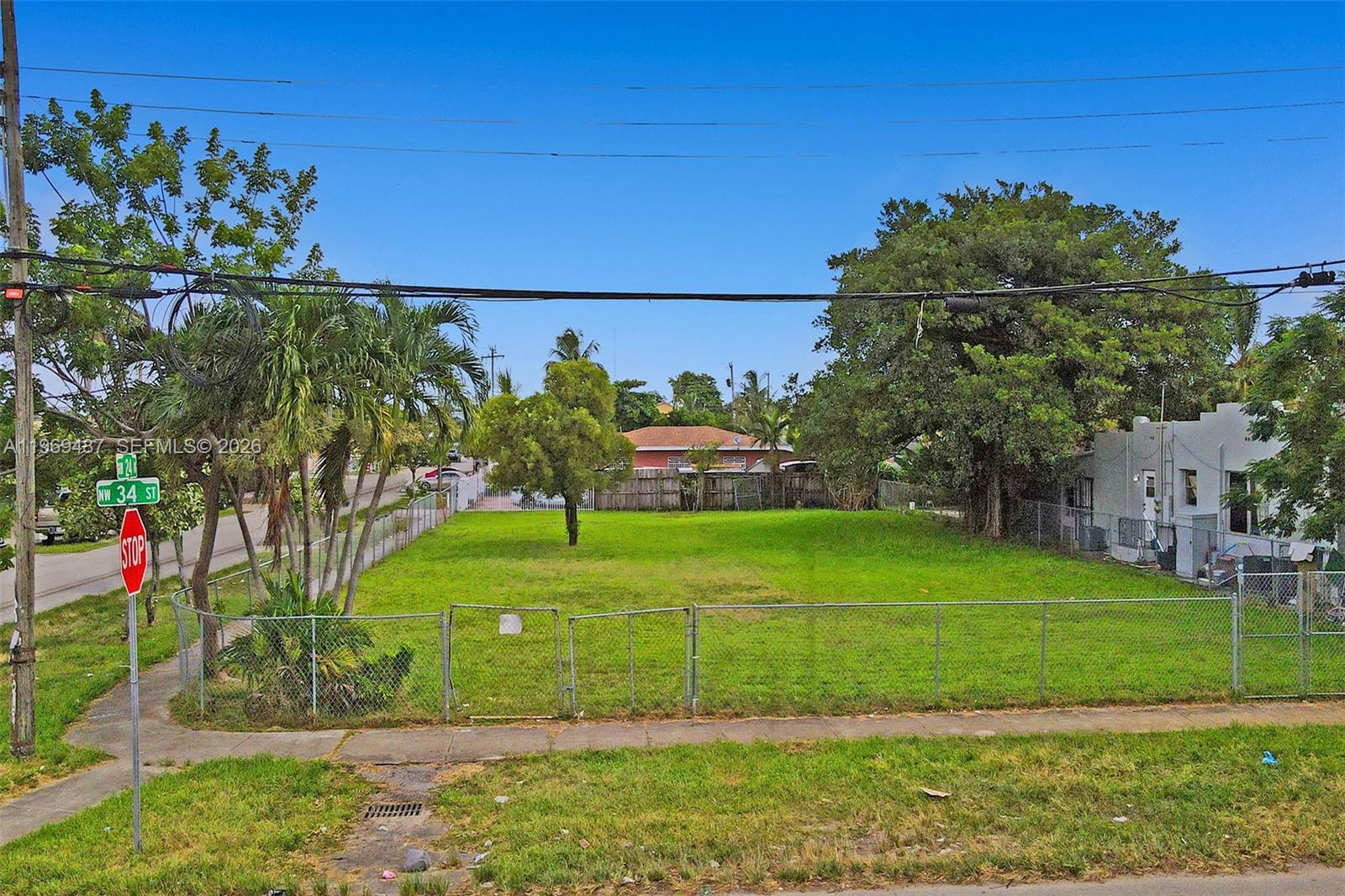 An aerial view shows a vacant, fenced-in grassy lot situated between two residential properties — 2397 NW 34th St, Miami FL 33142, MIAMI, FL