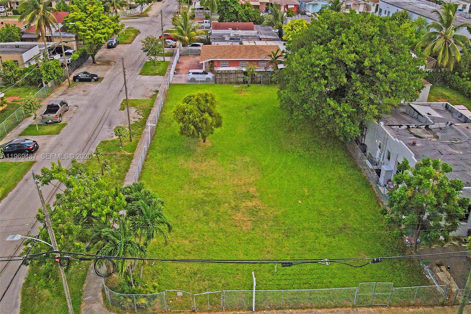A fenced, vacant grassy lot sits on a corner next to a residential building — 2397 NW 34th St, Miami FL 33142, MIAMI, FL