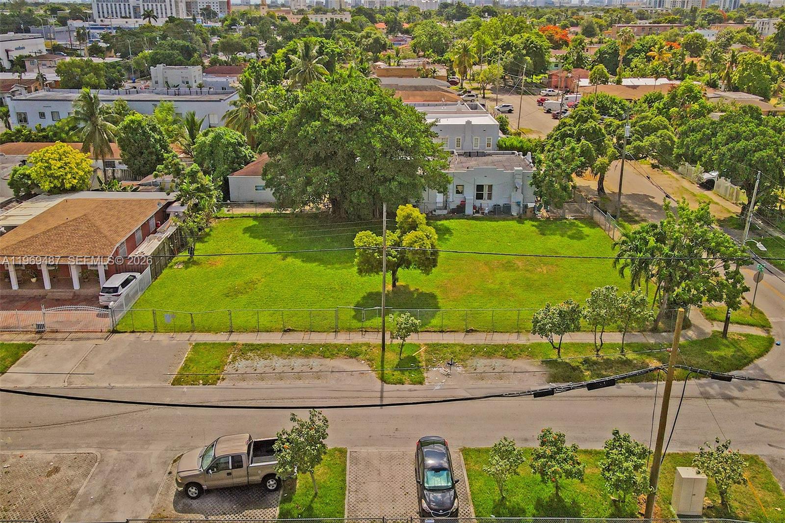 An aerial view shows a fenced, vacant grassy lot situated on a corner street intersection — 2397 NW 34th St, Miami FL 33142, MIAMI, FL
