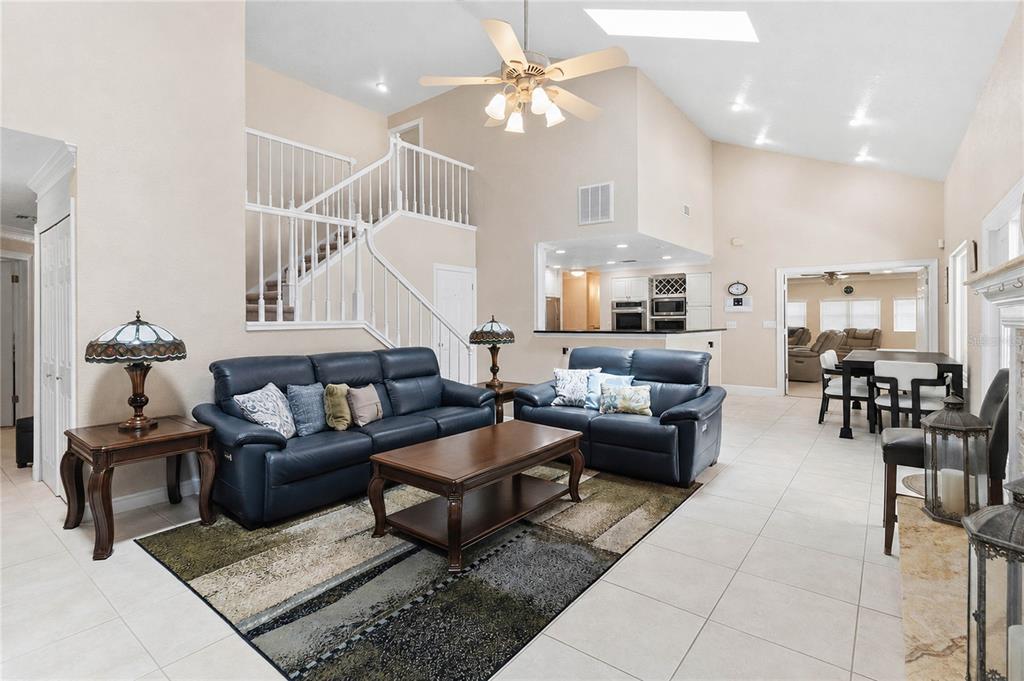 A living room with a staircase, leather sofas, a coffee table, and an open kitchen — 5333 GREENSIDE COURT, ORLANDO, FL